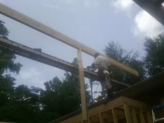 Carpenter setting a ridge beam over a new addition frame — Ice Dam Removal by Roofing Brothers in Burnham