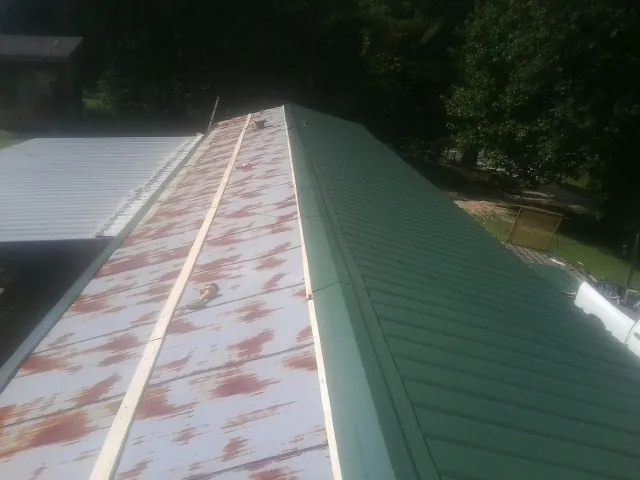 Old rusted panels beside newly installed green metal roofing — Wind Damage Roof Repair by Roofing Brothers in Burnham