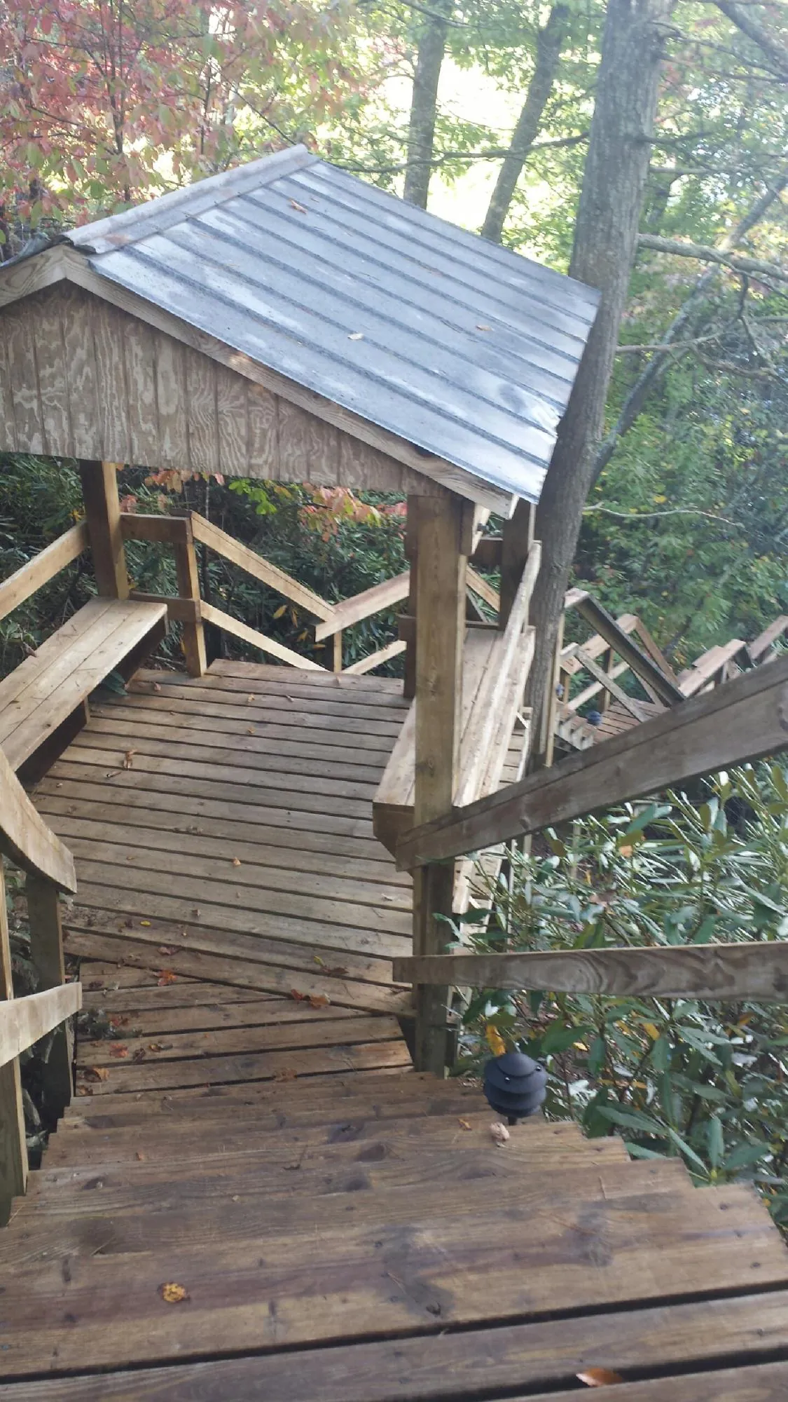 Metal roofed shelter over wooden steps on a wooded walkway — Skylight Repair & Installation work by our crew in Burnham