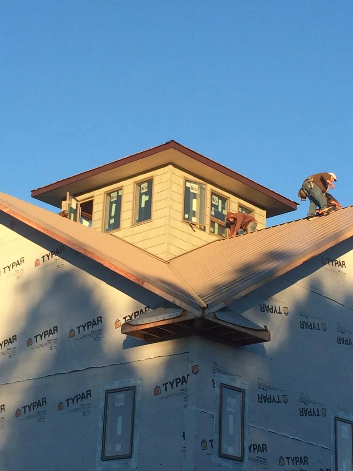 Roofers working around a rooftop cupola on a new metal roof at sunset — Roof Waterproofing in Burnham by Roofing Brothers